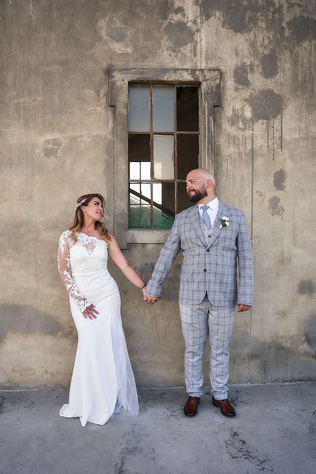 kézenfogva álló házaspár a rácsos ablak előtt