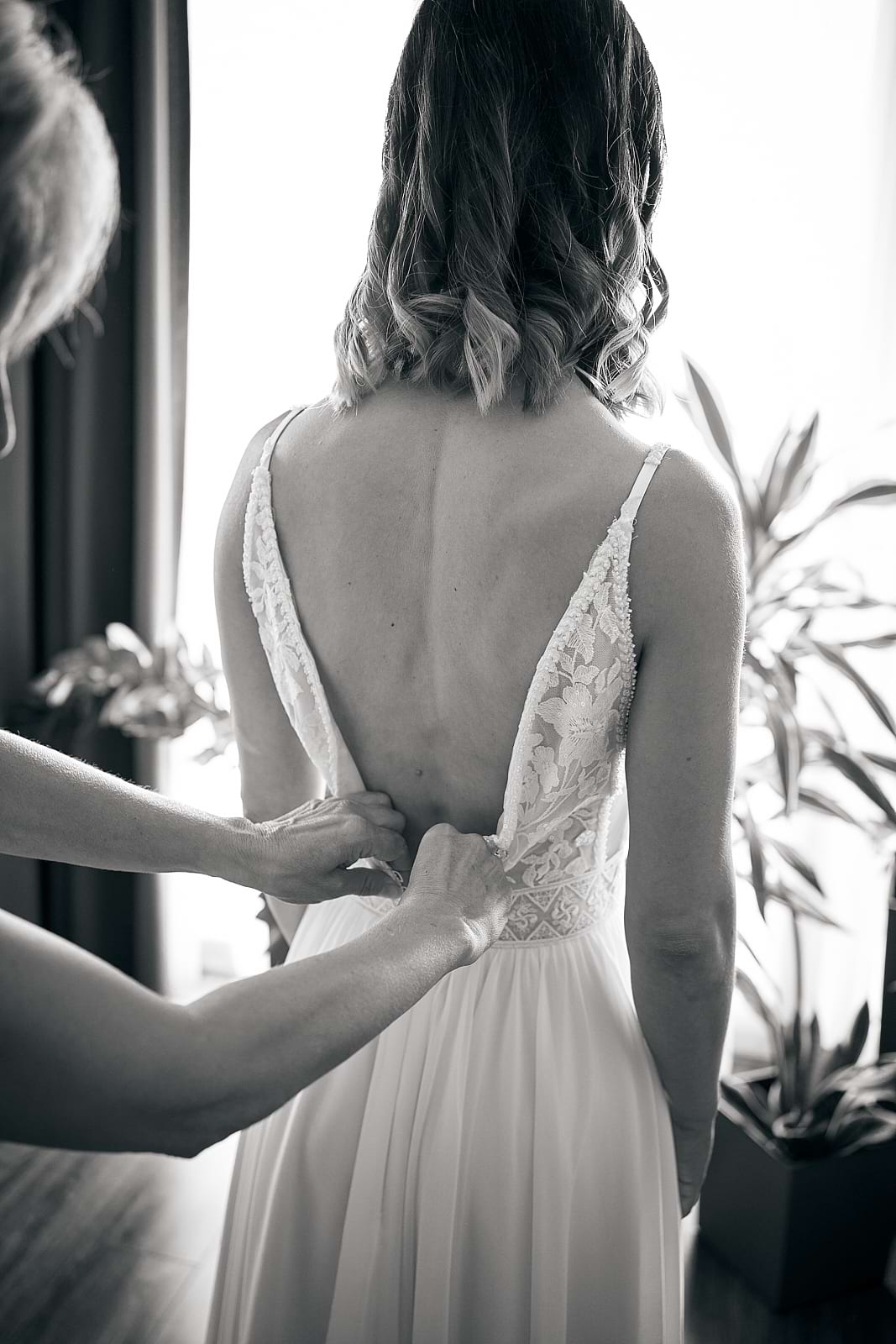 Orsi menyasszonyi ruháját csatolja össze egy segítő fekete fehérben