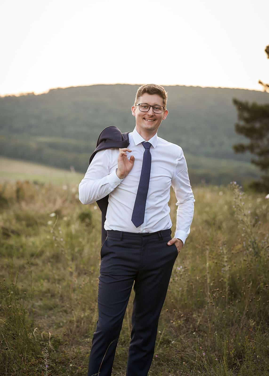 Attila válla mögött tartja zakóját