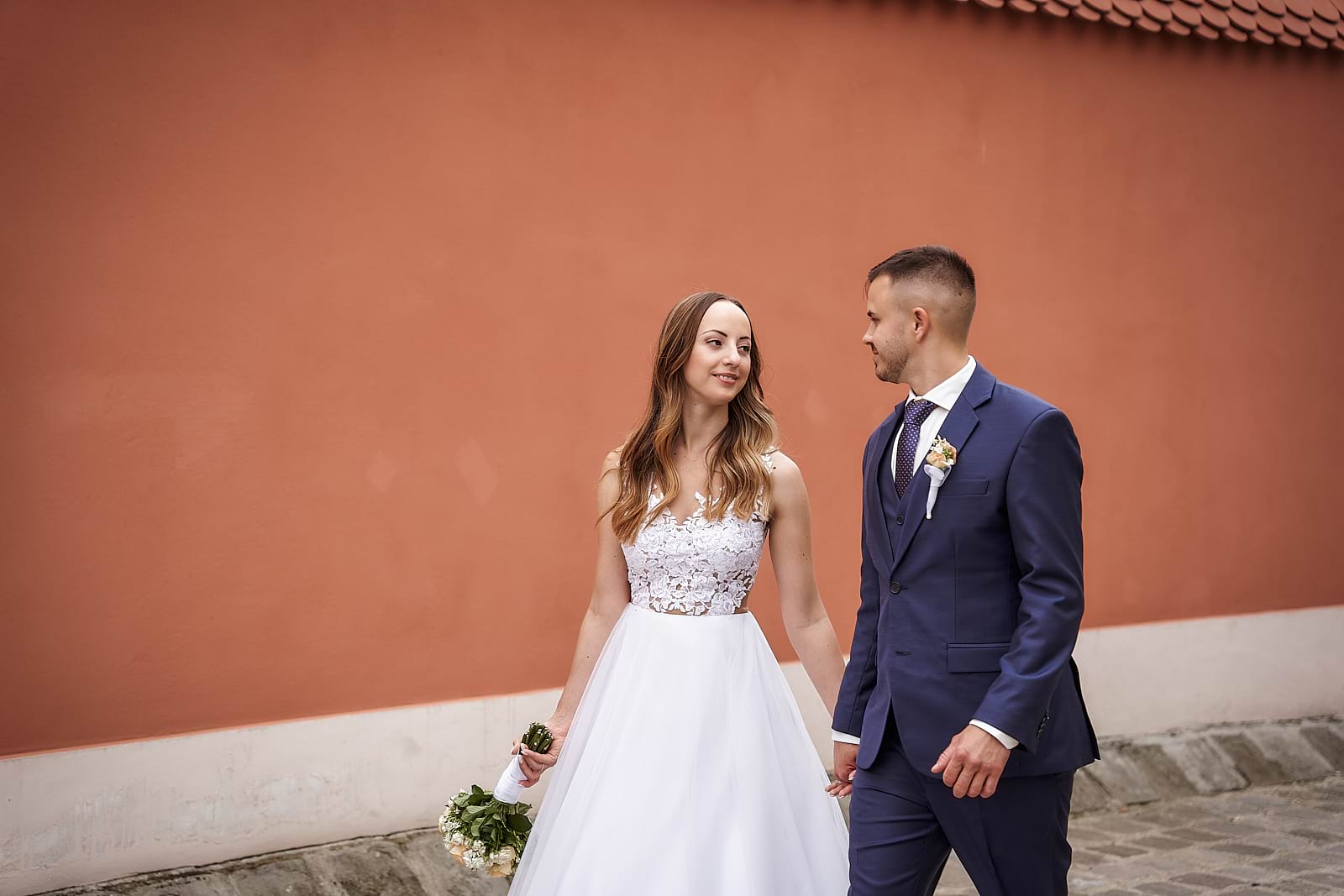 Vivi és Ricsi a narancssárga fal előtt sétálnak el